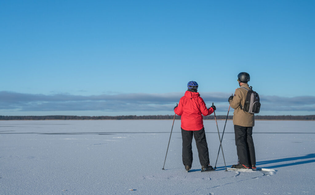 Par som åker långfärdsskridskor på sjön. Foto.